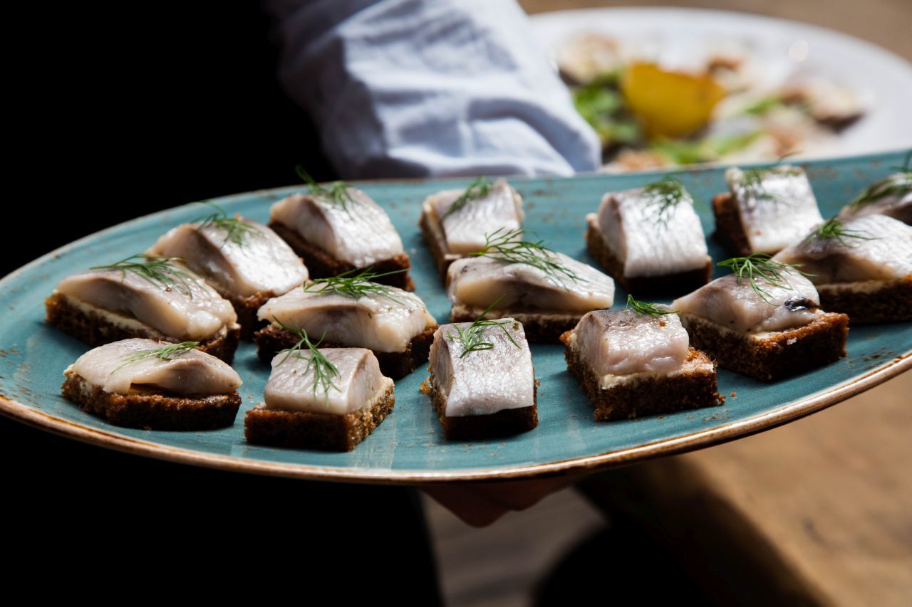 Pieces of fresh herring with dill atop rye bread.