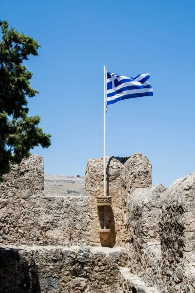 Lindos is for TouristsThe Greek flag waving in the breeze at the castle ruins of Lindos.