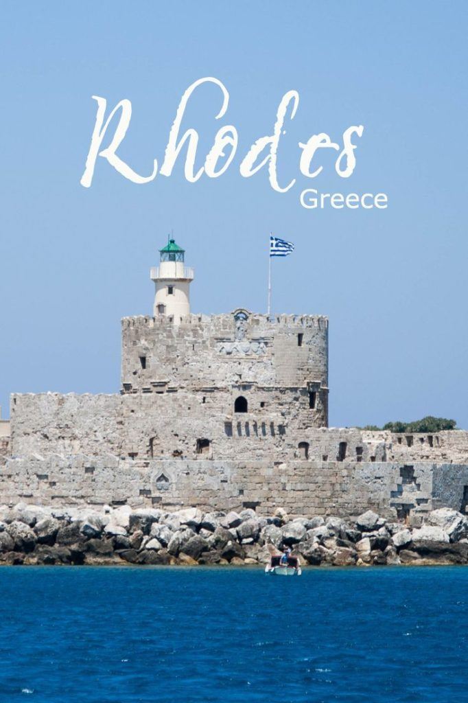 Rhodes defensive tower with lighthouse and Greek flag.