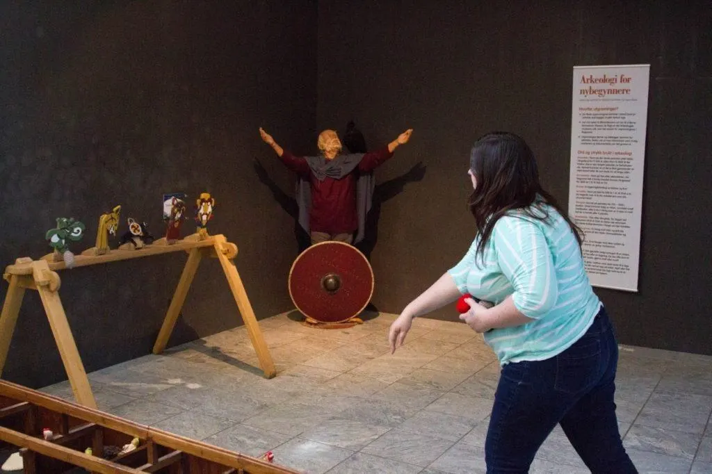 A girl throwing balls at toys in the Viking museum in Stavanger.