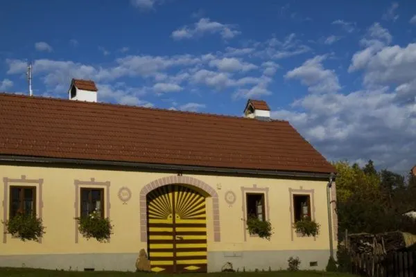Gorgeous yellow barn with terracotta tiled roof under a perfect blue sky in Holašovice.
