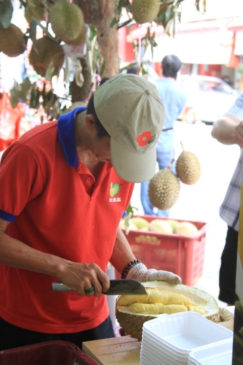 Durian vendor cutting fruit.