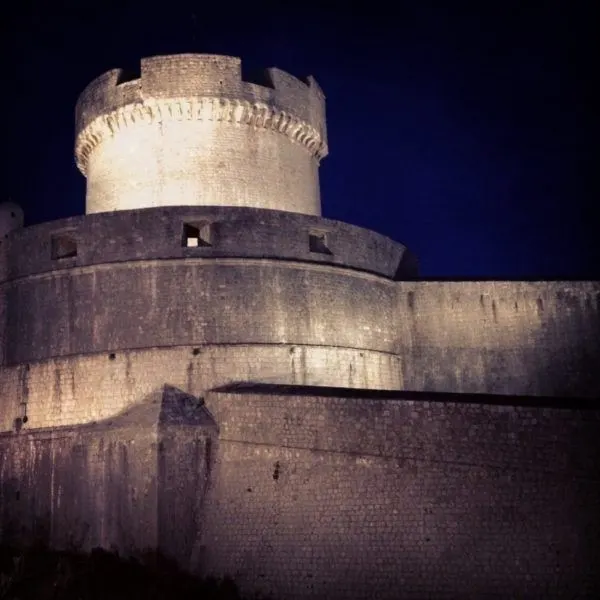 Dubrovnik city wall and defensive tower at night.