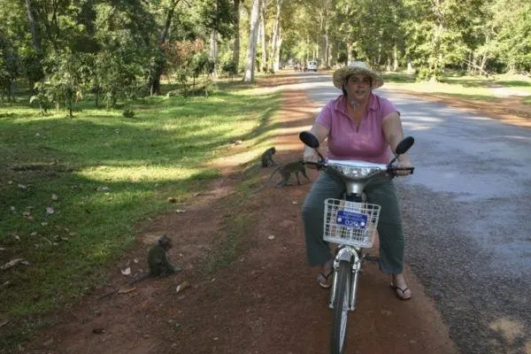 Corinne on her electric bike surrounded by monkeys in Angkor Wat.