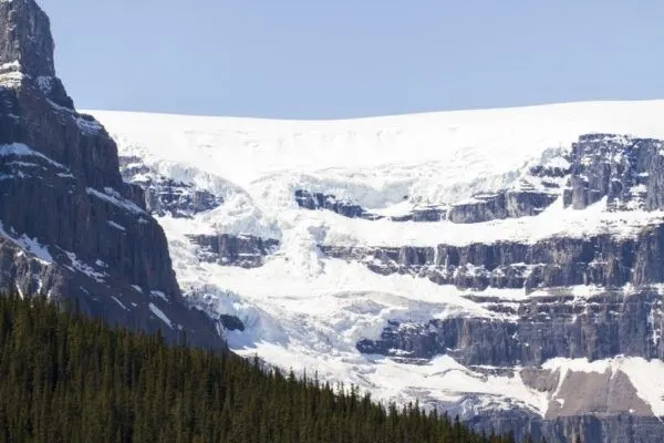 Massive glacier hangs over the edge of a cliff.