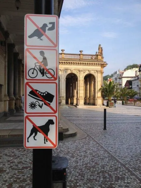 Karlovy Vary pedestrian zone advisory sign - no feeding the pigeons, no biking, stay off the flowers, no dogs.