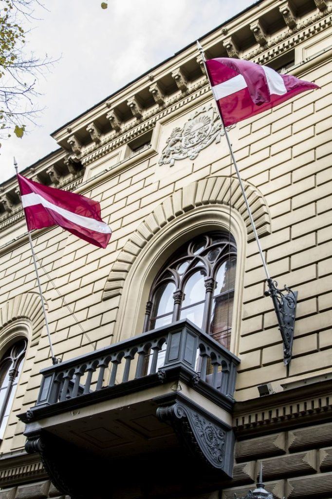 Latvian flags fly in front of a government building in Riga.