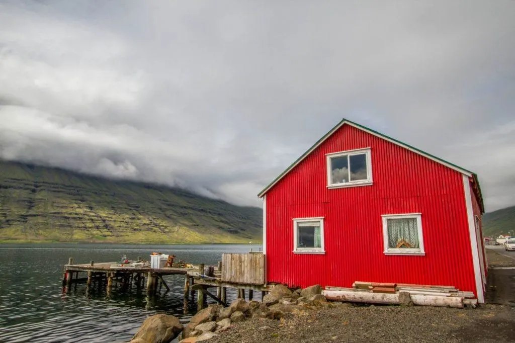Traditional red with white trim boat house on an Icelandic fjord.