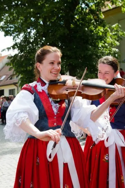 Two women in traditional Czech dress play the violin for folk dancers at Ride of the Kings in Vlčnov.