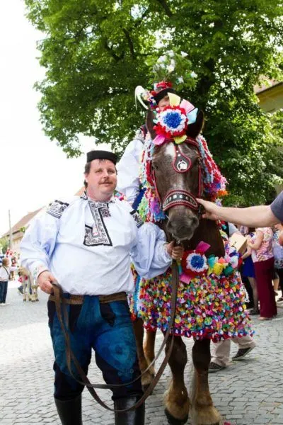 The young camouflaged king sits high atop a colorfully decorated horst at the Ride of the Kings in Czechia.