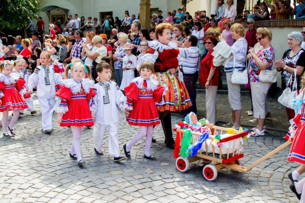 Children in traditional Czech costume pulling a decorated wagon at the Ride of the Kings in Vlčnov.