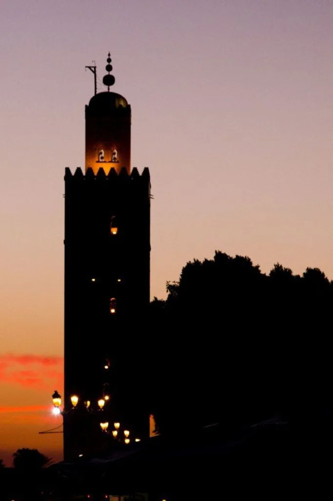 Marrakesh with a silhouetted mosque tower at sunset.