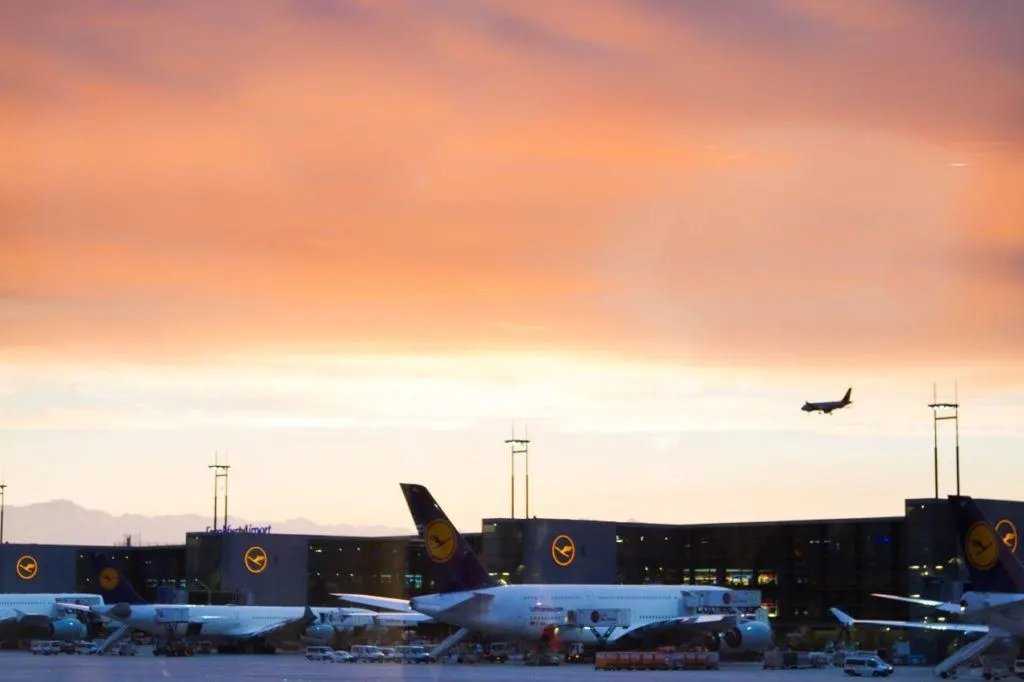 Lufthansa jets shining in the golden glow as the sun sets behind Frankfurt Airport.