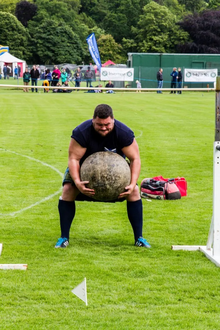 Man lifting a huge stone, unique to the Inverness Highland Games.