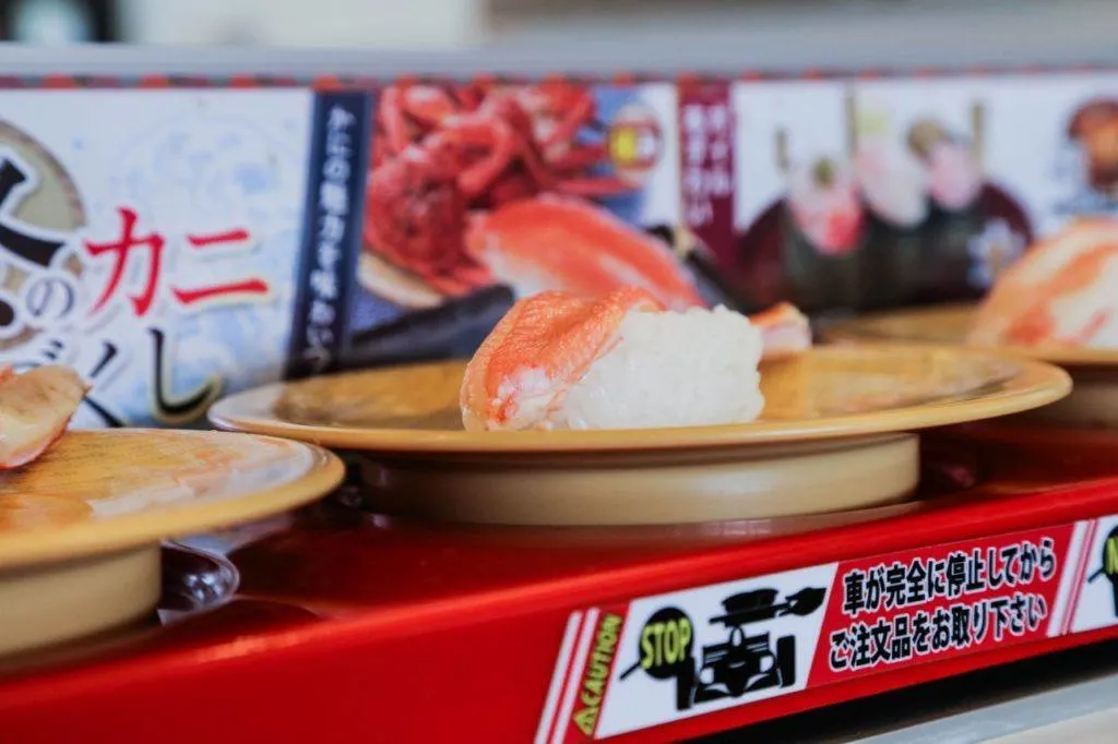 Crab sushi being delivered on a sushi train to the table. A popular Japanese dish to add to your Japan food guide. 