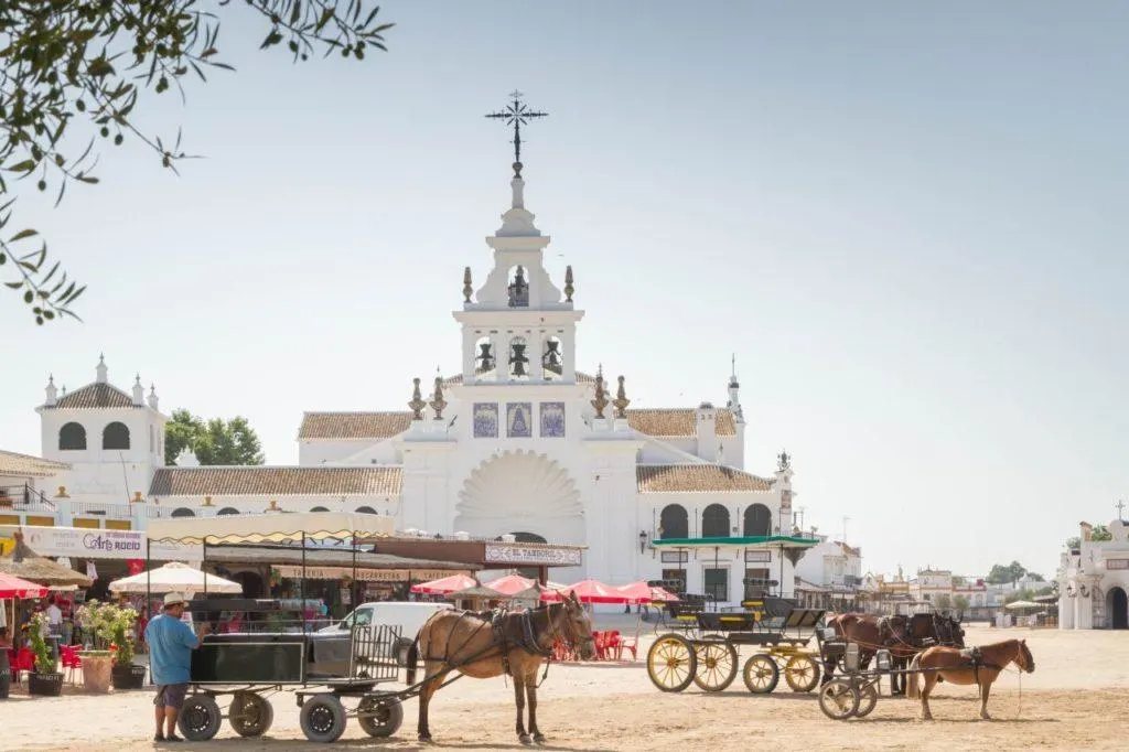 Horse carts and wagons are waiting for passengers outside the cathedral in El Rocio.
