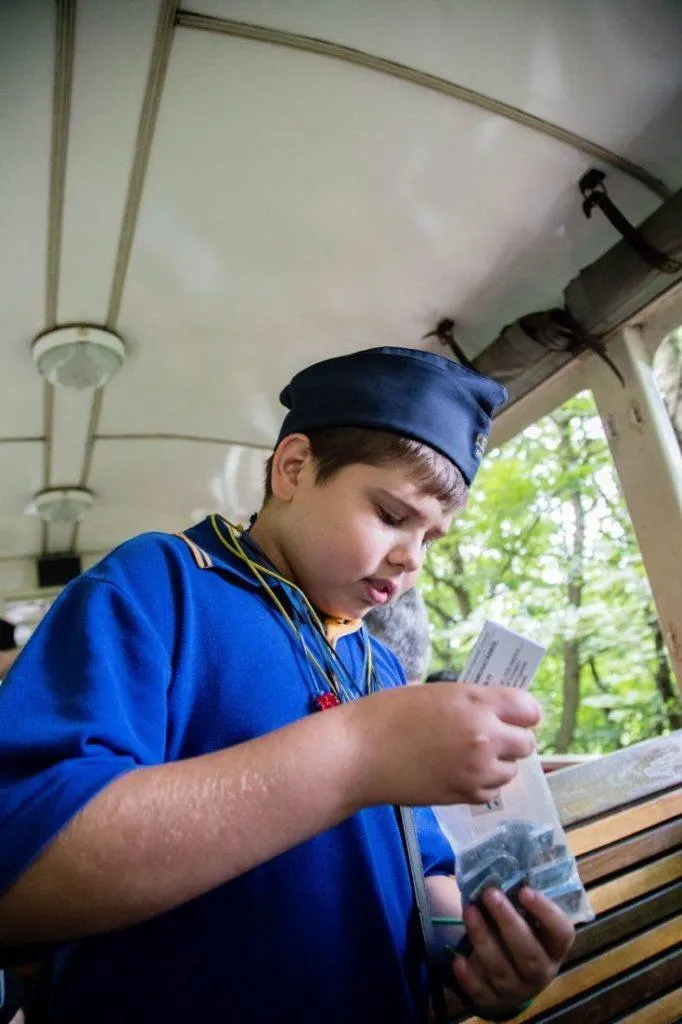 A young conductor in his bright blue uniform collects tickets on the train.