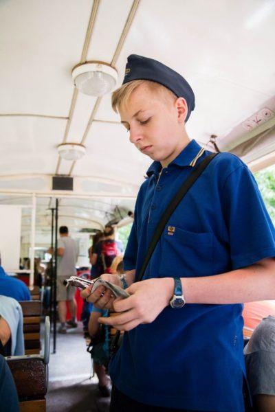 Teen conductor takes tickets and sells souvenirs aboard the children's railway in Budapest.