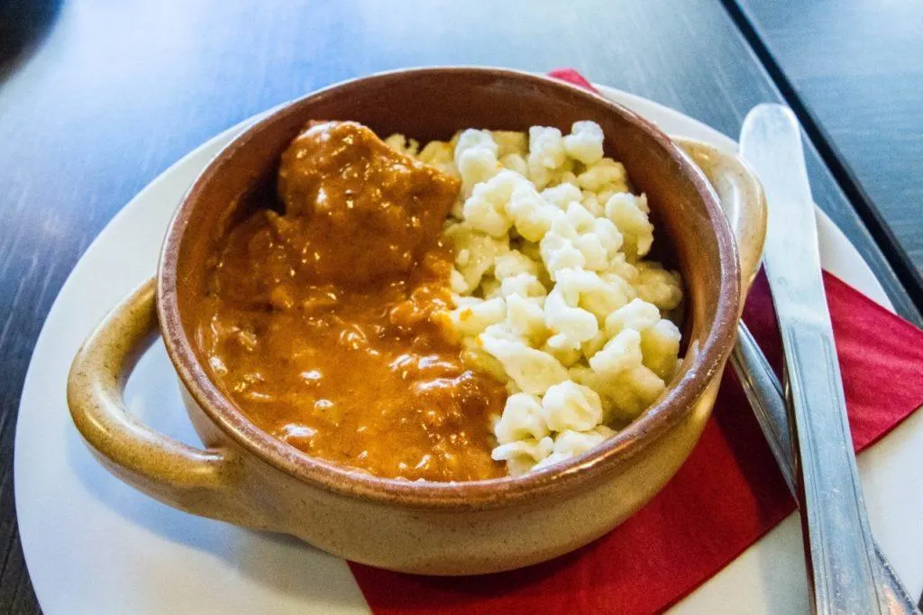 Chicken paprikash with spaetzle served up in a crock-ware bowl.