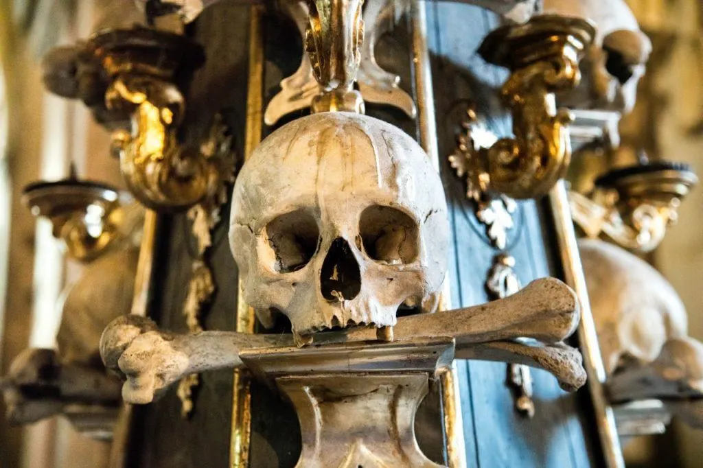Human Skull with bone in mouth make up part of the decorations in Sedlec Bone Church in Kutna Hora, Czechia.