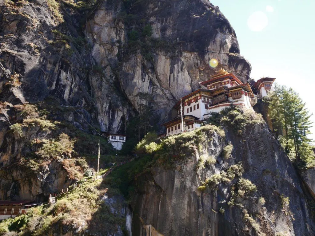 White washed temple with painted roofs and pagoda on a cliff in Bhutan.
