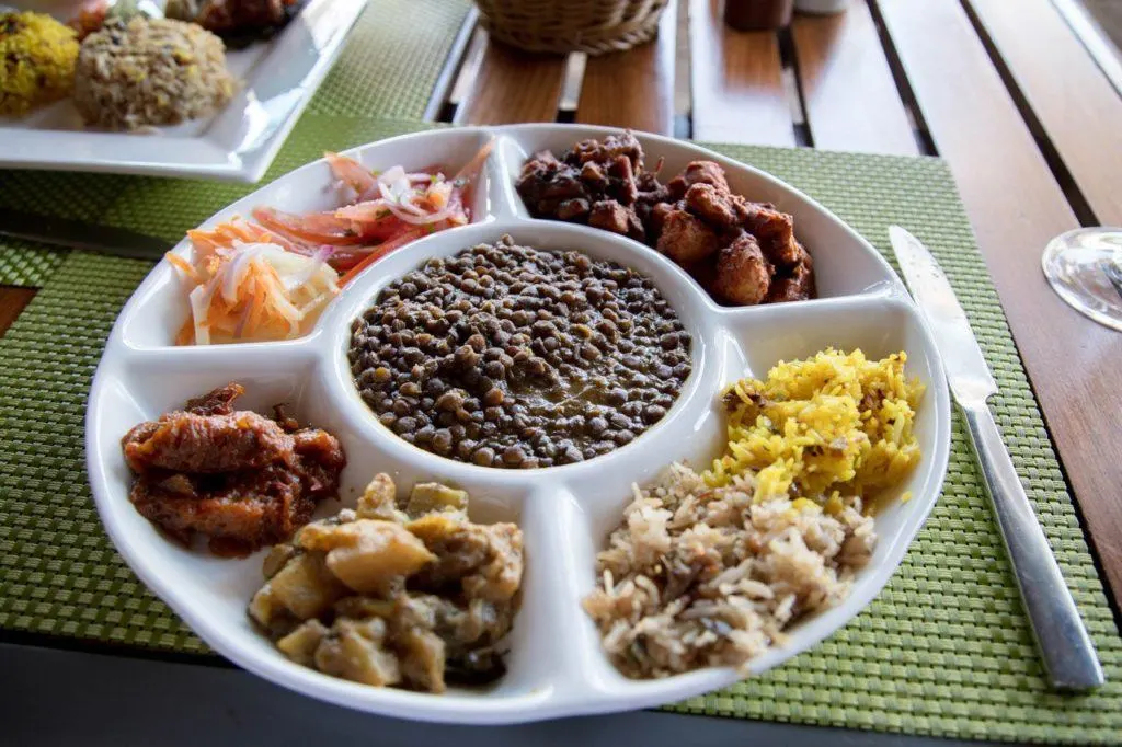 Traditional Mauritian taster plate with lentils, curries, and biryani.