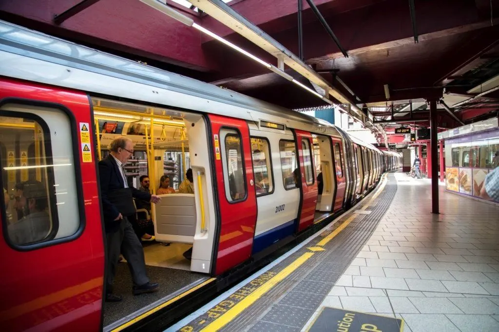 London tube train opens doors at station.