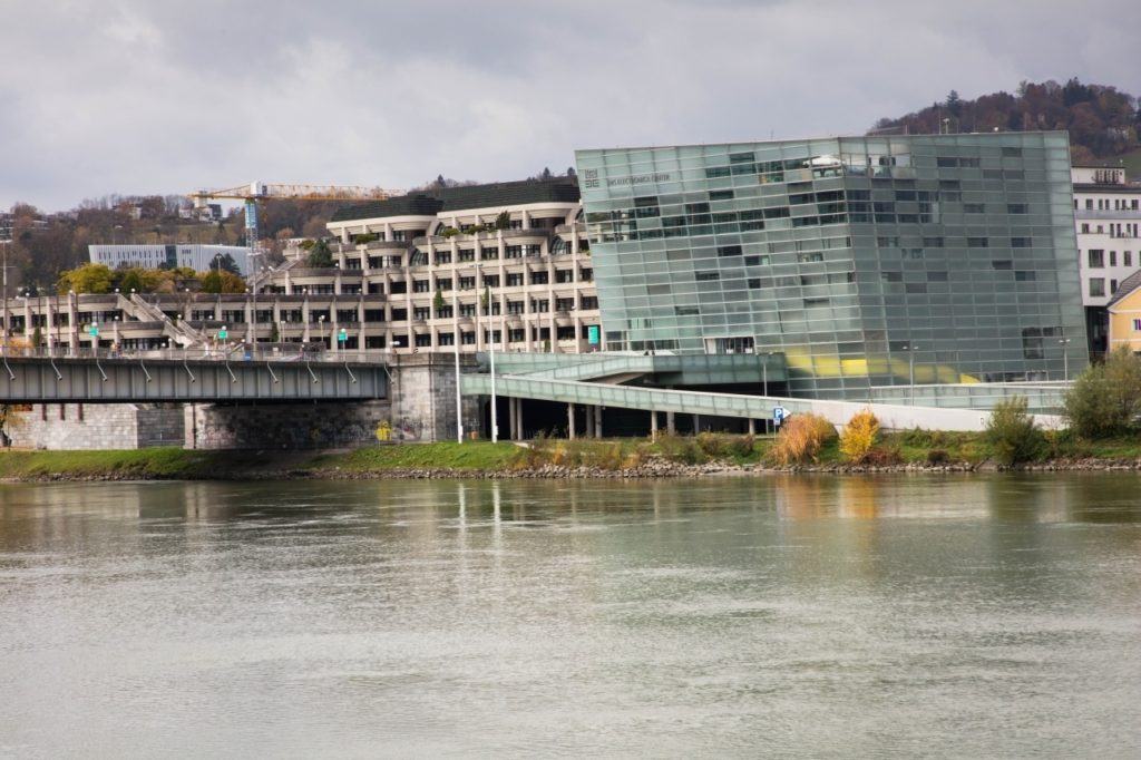 A Donau river and view of the opposite bank with one modern blue building, and one beige.