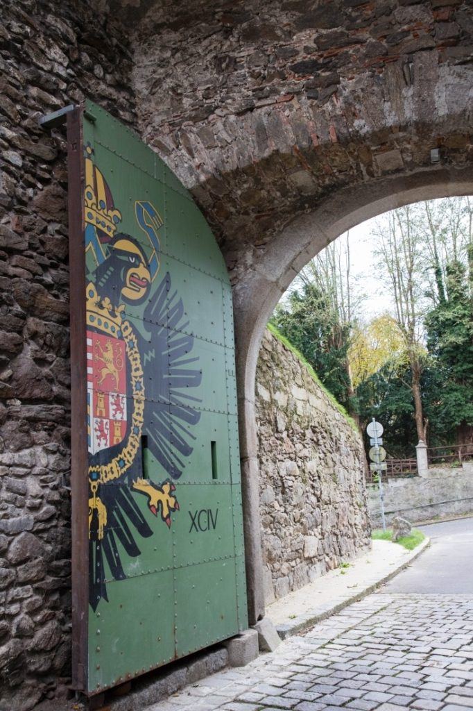 A stone archway filled with a half door painted green with an eagle on it.