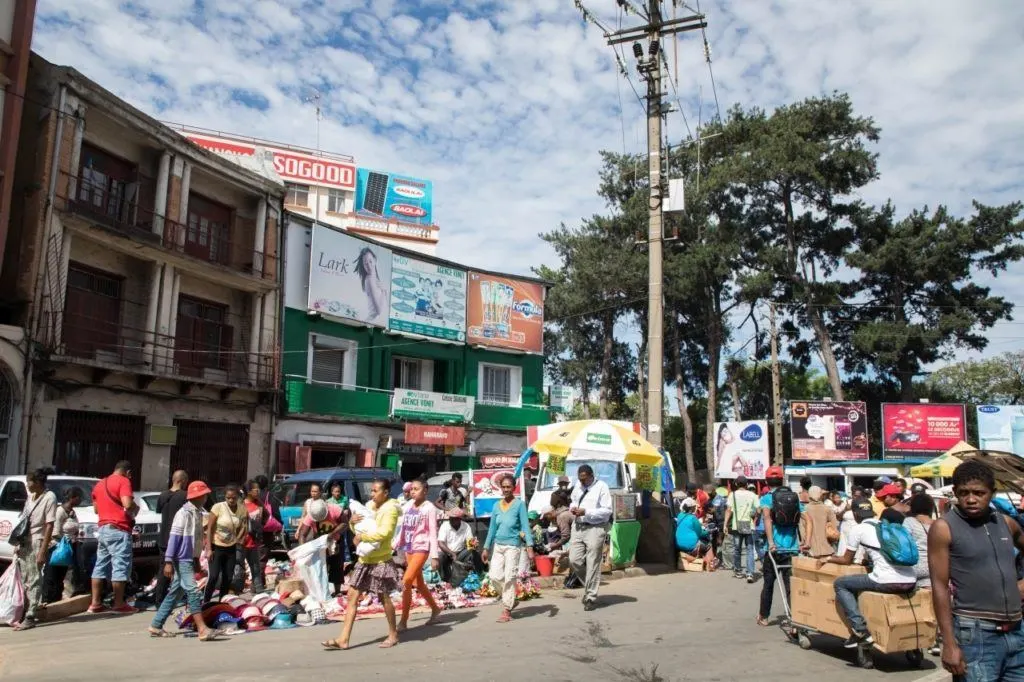 Antananarivo city scene with lots of people walking and things for sale on the sidewalk.