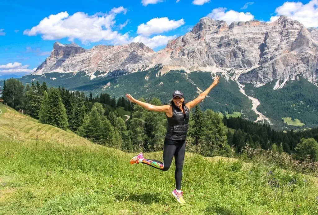 Girl smiling and kicking foot up in Italy's Dolomite mountains.