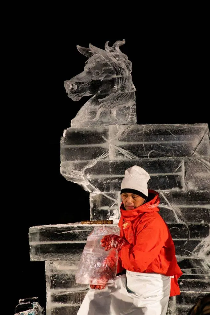 Artist taking off big chunks for his horse he is carving for is magnificent ice sculpture.