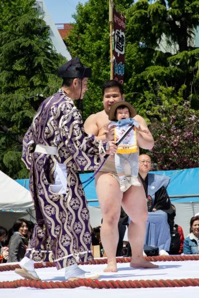Sumo wrestler with crying baby.