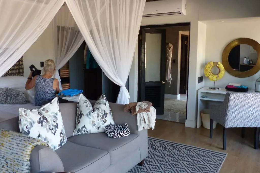 The interior of a Thornybush Game Lodge bungalow with mosquito-netted beds, a sitting area, and spacious bath.