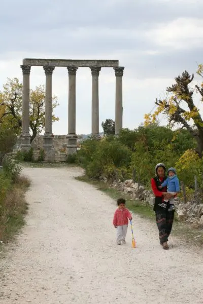 Zeus' Temple columns and a family walking in Uzuncaburç.