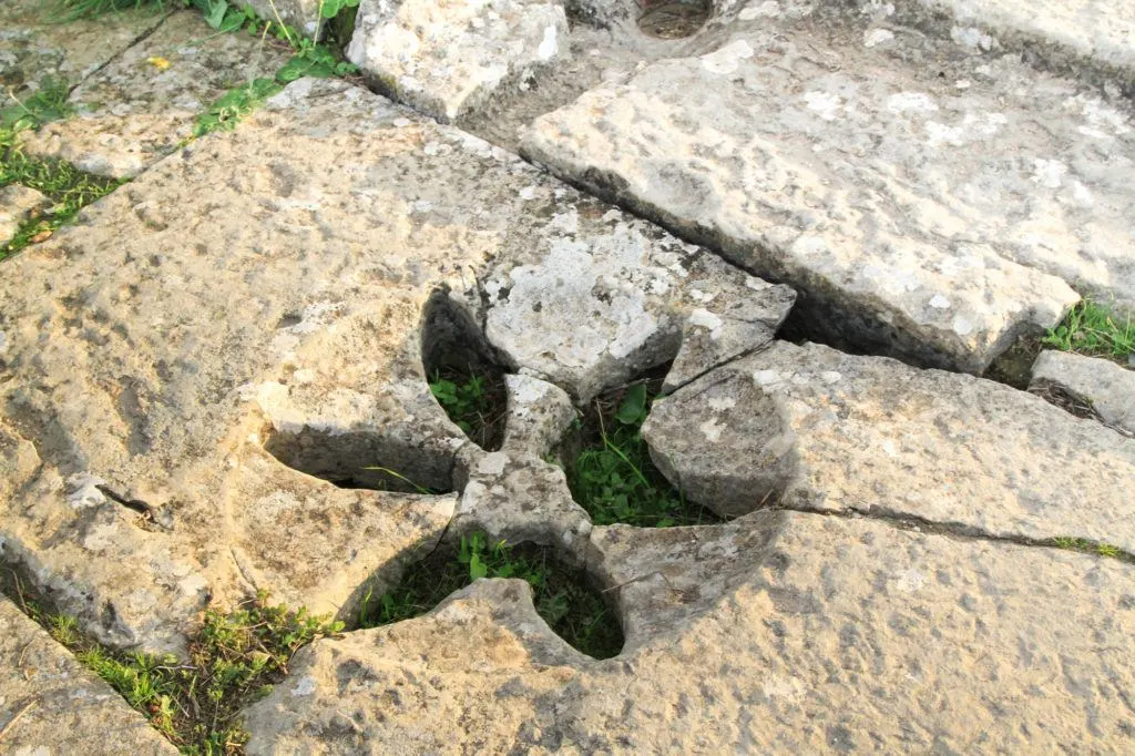 A broken stone carved with a decorative floral design lying on the ground at the Roman ruins in Volubilis.