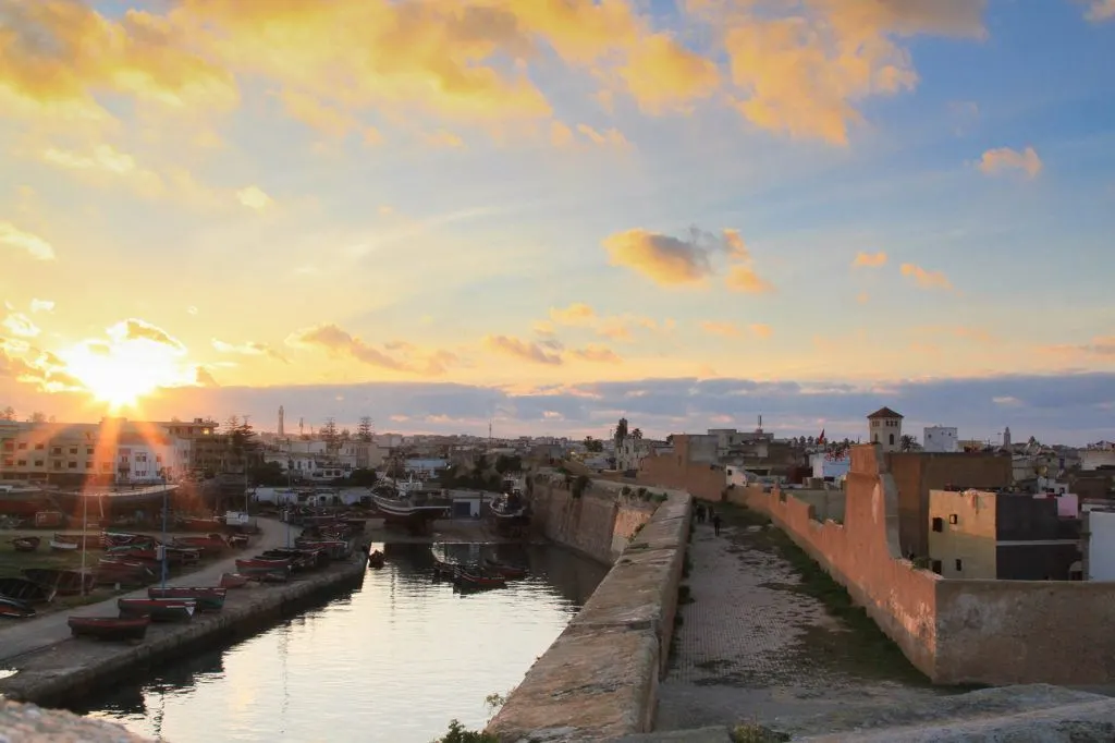 The sun sets behind the stone walls and canal in El Jadida, Morocco.