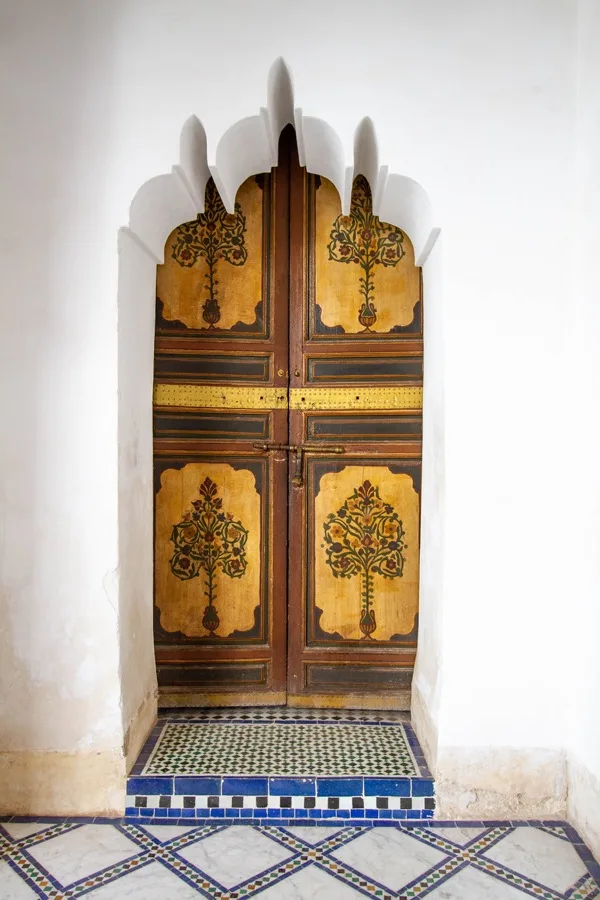 A door with painted panels inside an intricately shaped archway in Marrakech.
