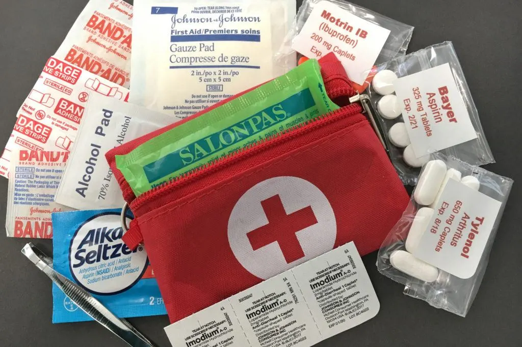A tiny 3 x 4 inch first aid kit with basics like aspirin, alka seltzer, alcohol pads, tweezers, and assorted band aids.