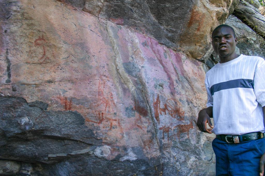 As our San guide stands beside a rock painted with animal figures, he shares the history, and legends of the San people.