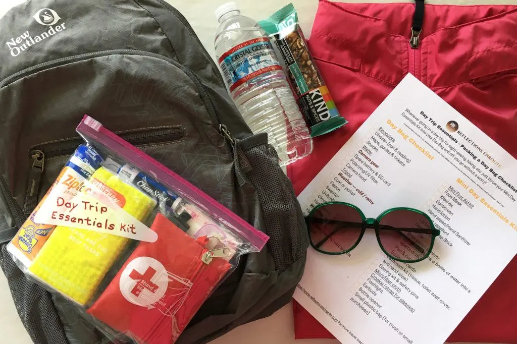 A small day bag with the mini day trip essentials kit, a copy of out day trip check list, and a few typical day bag items.