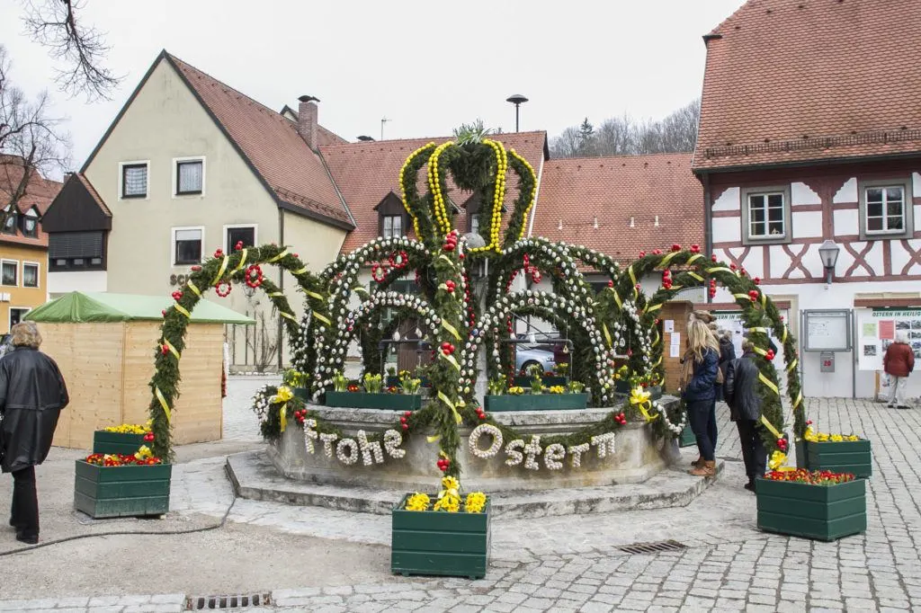 Frohe Ostern, or Happy Easter. People marveling at the intricate design of this Osterbrunnen.
