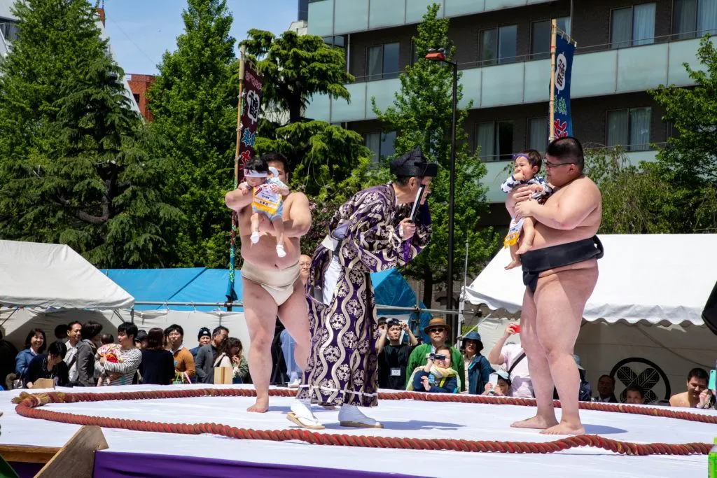Sumo wrestlers, babies, and referee during the nakizumo competition, a spring festival in Japan.