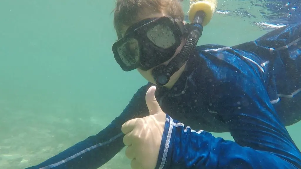 Snorkeling on vacation, this boy is giving a thumbs up.