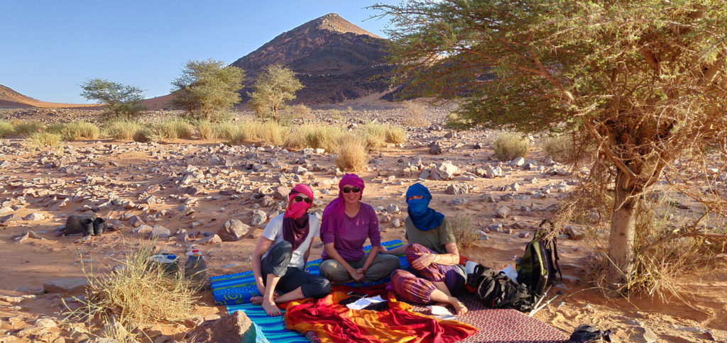 A group of desert hikers take a rest in the shade.