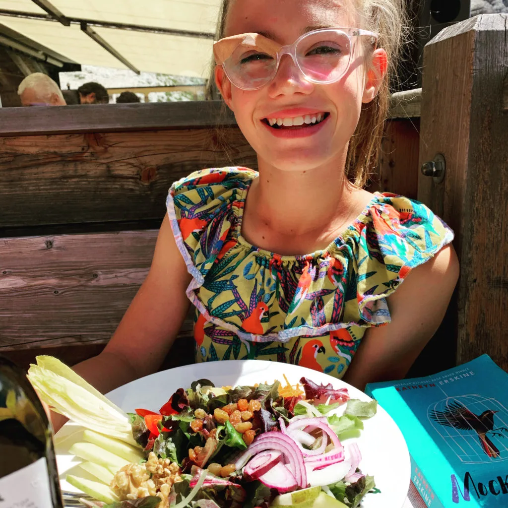 The food is surprising good, as this girl smiles, while hiking the Dolomites.