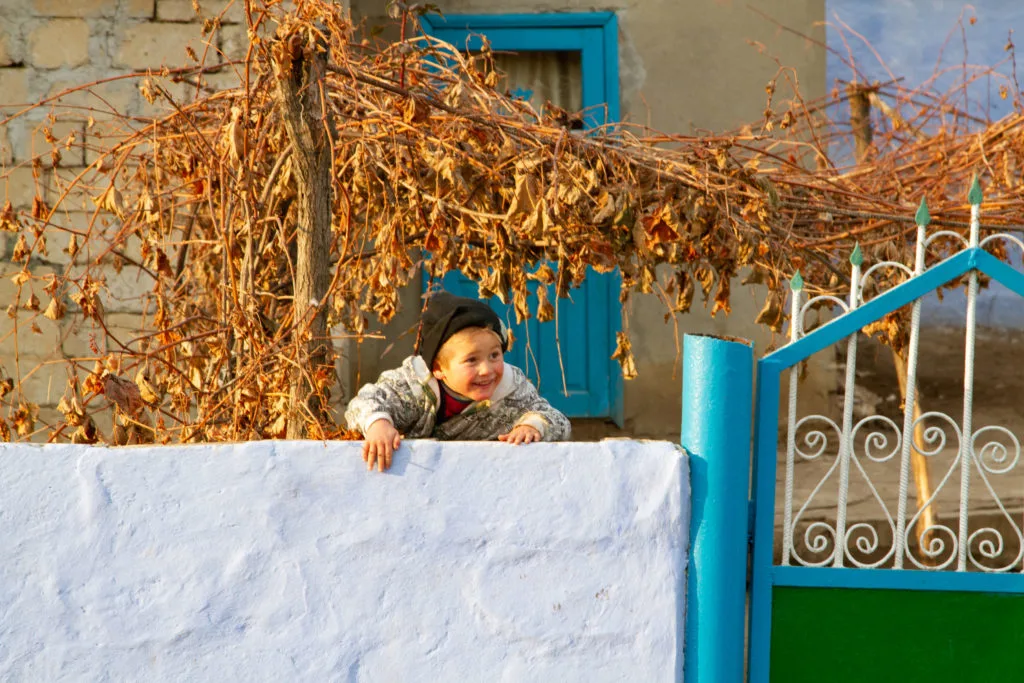 A child jumps up to see the tourists in the countryside of Moldova.