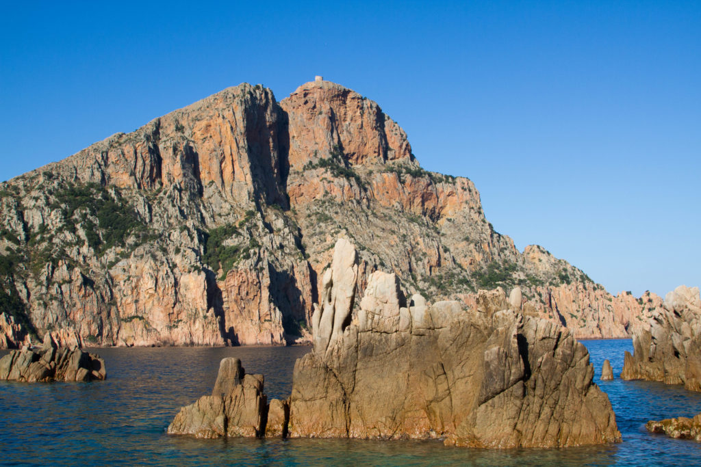 A tiny tower peeks over the scandola nature reserve cliffs.