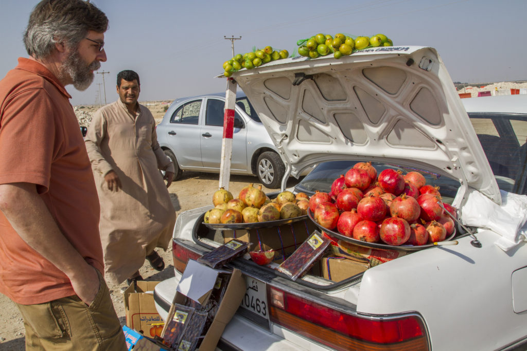 A Qatari man sells fresh fruit out of his trunk.