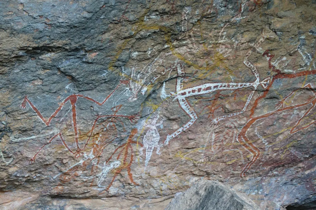 An Aboriginal rock art painting of a ceremony or gathering with music and figures dancing.